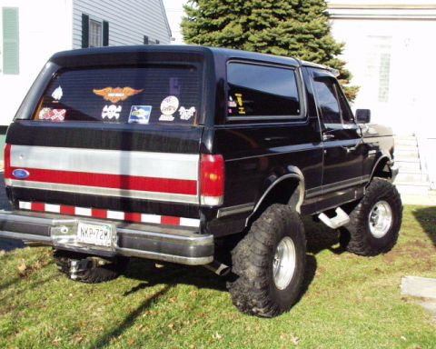 1989 Ford Bronco - This lifted 1989 Ford Bronco features large off-road tires and custom red and silver stripe accents on the rear.