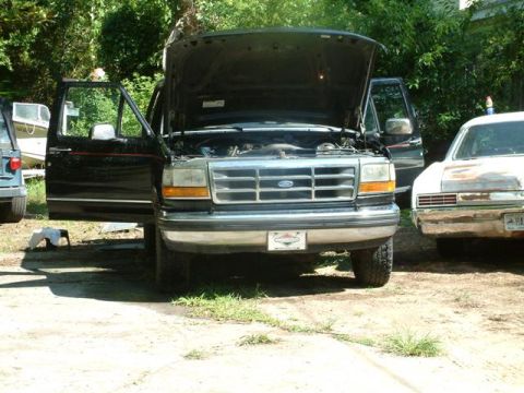 1992 Ford Bronco - A black 1992 Ford F-150 truck is parked with its hood and doors open, showing its engine and interior.