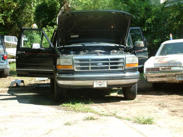 Black 1992 Ford F-150 truck with hood and doors open, parked outdoors