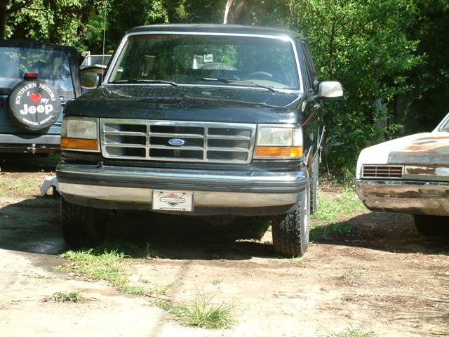 Front view of a black Ford F-Series truck. A Jeep is to the left, and another vehicle is to the right