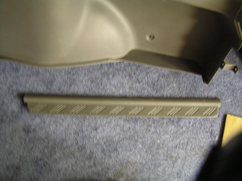 1993 Ford Probe - A gray plastic interior trim piece with a textured pattern is shown against a blue fabric background.