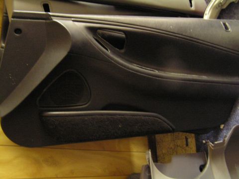 1993 Ford Probe - This is a black interior door panel with a speaker grille and fabric insert, likely from a car part sale.