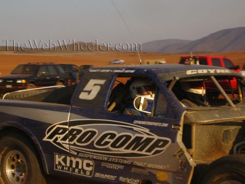 1990 Ford Bronco - close-up of a blue number 5 off-road race truck with Pro Comp, KMC Wheels and Coyne sponsor decals in a dusty pit.
