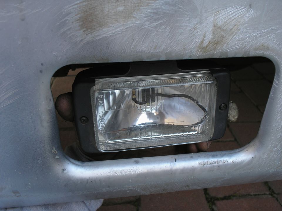 Rectangular halogen fog lamp being fitted into an aluminum bumper opening