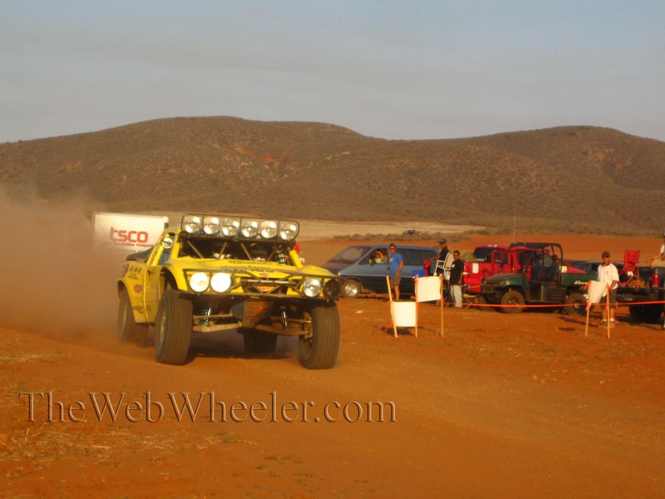 Yellow off-road race truck with roof light bar on dusty desert road