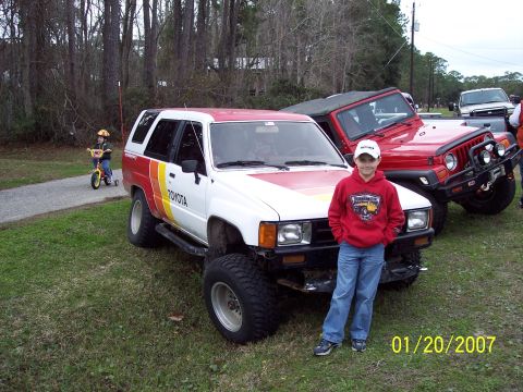 1984 Toyota 4Runner - A boy stands next to a modified 1984 Toyota 4Runner at an outdoor event.