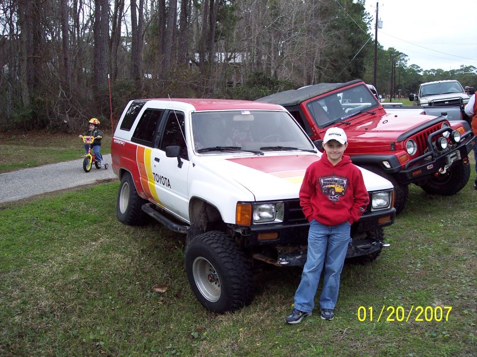 White Toyota 4Runner with red and yellow stripes, lifted suspension, and off-road tires