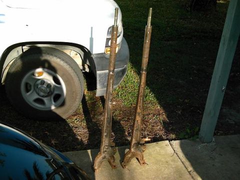 1986 Ford Bronco - Two old, rusty metal suspension components are displayed next to a white pickup truck.
