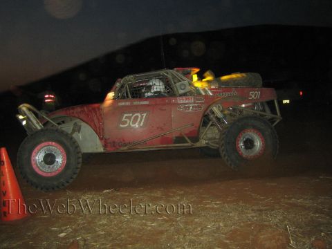 1990 Ford Bronco - Red off-road race buggy number 501 with red wheels sits on a dark desert course at night beside a traffic cone.