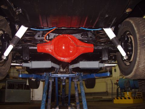 1972 Ford Ranchero - The rear axle assembly and exhaust system of a vehicle are visible from below, supported by a lift.