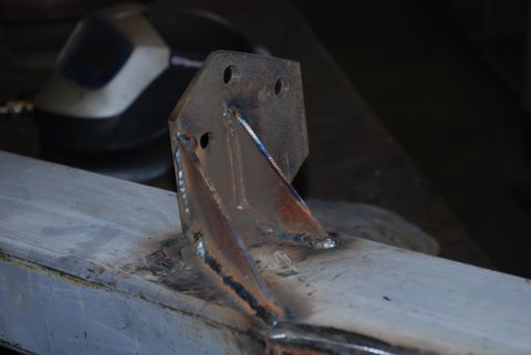 1996 Ford Bronco - A close-up view of a metal bracket being welded onto a beam, with a welding mask visible in the blurred background.