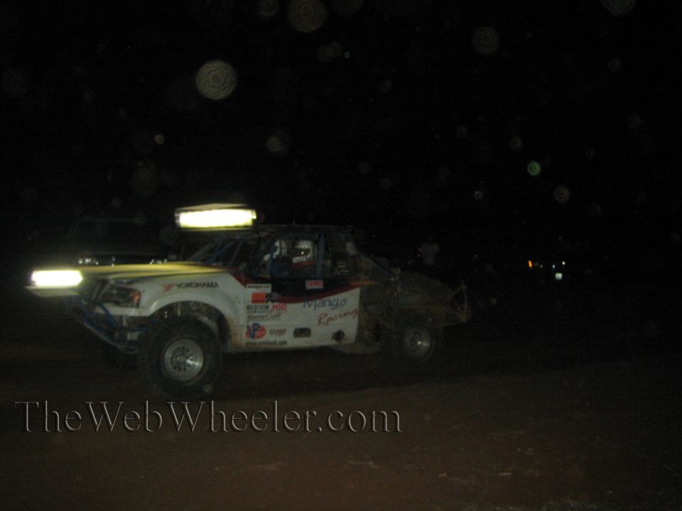 White Mango Racing off-road race truck at night with yellow light bars