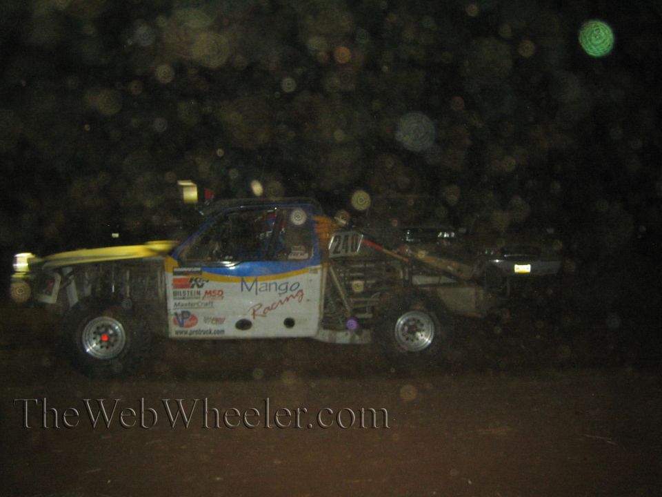 White and blue Mango Racing off-road race truck at night on dirt