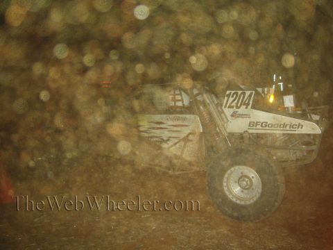 1990 Ford Bronco - white number 1204 off-road race buggy with a BFGoodrich decal races at night through a heavy dust haze.