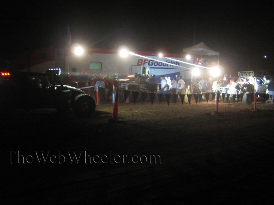 Off-road race pit at night with BFGoodrich banner, floodlights and crowd