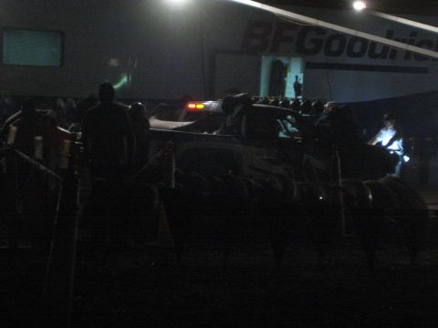 1990 Ford Bronco - off-road race truck and crew silhouettes occupy a dim pit area at night under a BFGoodrich banner.