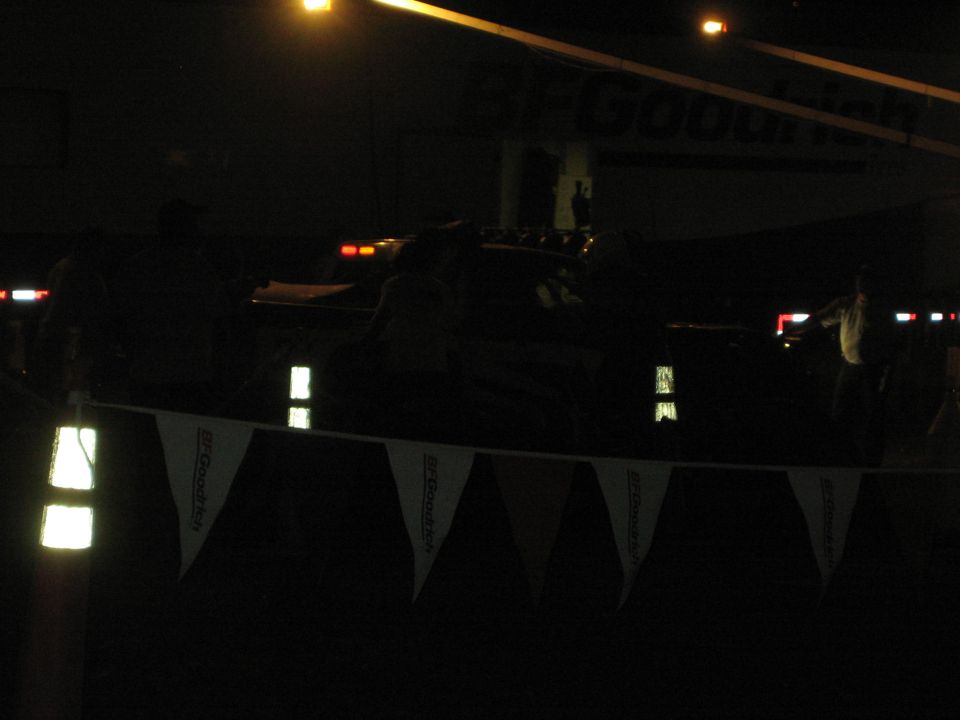Dark nighttime race pit with BFGoodrich bunting and faint vehicle lights