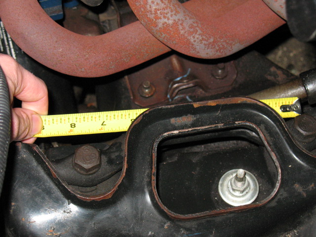 hand holding tape measure to engine component