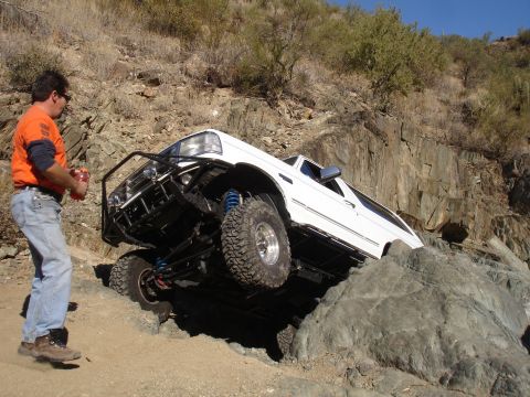 1993 Ford Bronco - A white Ford Bronco attempts to climb over large rocks on a steep, off-road trail.