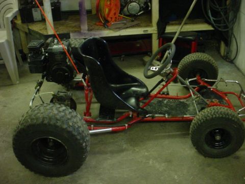 1990 Ford Bronco - A go-kart sits in a garage with its engine and steering wheel clearly visible.