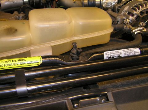 2000 Ford Excursion - Remove the lug-nut wrench from under the hood of your Excursion. We'll use the end with the rubber tip to remove the beauty cap on the fron…