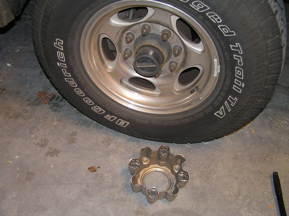 Alloy wheel with BFGoodrich tire and removed hub lock assembly on garage floor