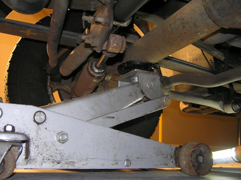 Floor jack supporting a vehicle's rear leaf spring and axle from underneath