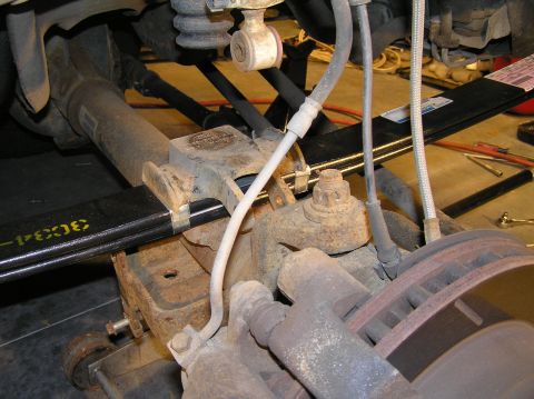 2000 Ford Excursion - Reinstall the bump-stop/u-bolt plate. The notch in the bump-stop lines up with the nut on top of the leaf spring.