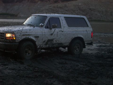 1993 Ford Bronco - This white 1993 Ford Bronco is stuck in the mud, showing its side profile.