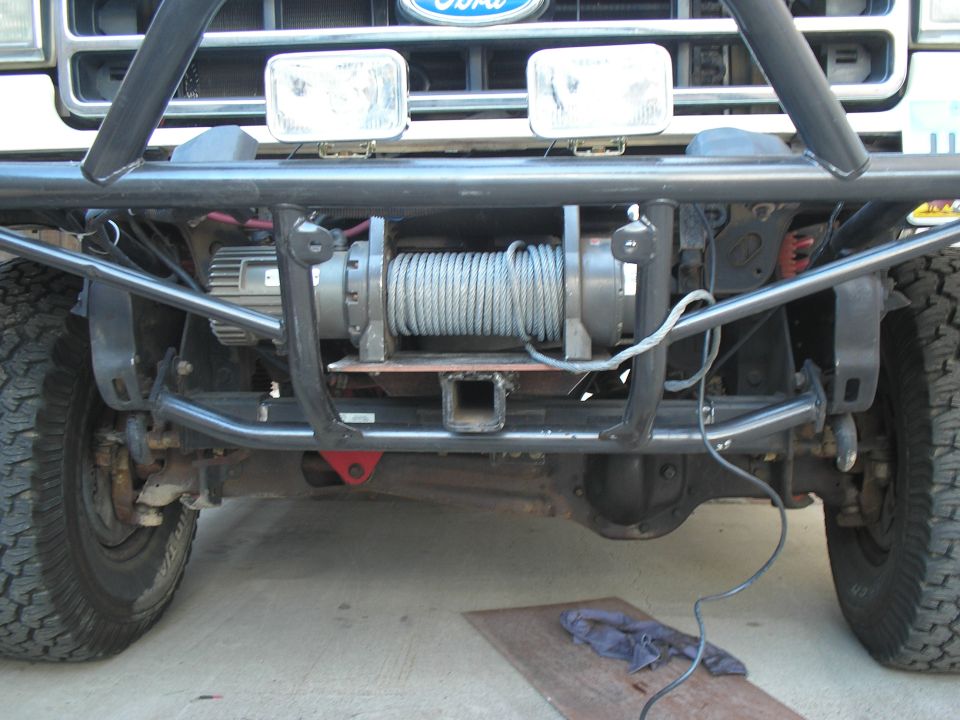 Front winch and steel cable mounted behind a black tube bumper on a Ford 4x4