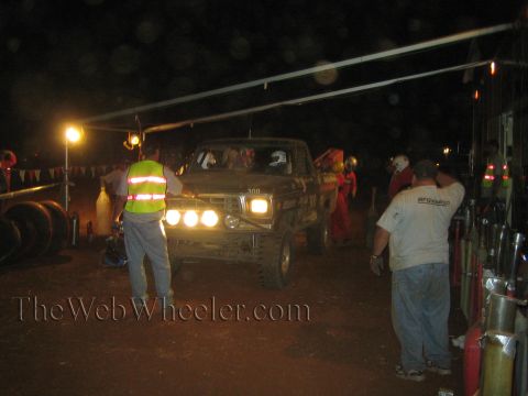 Dark number 300 off-road truck at night pit with crew and lights