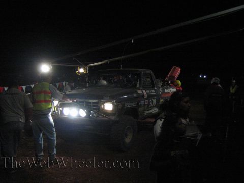 Number 300 off-road truck with lights on among crowd at night