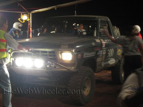 Front of black number 300 off-road truck with auxiliary lights lit