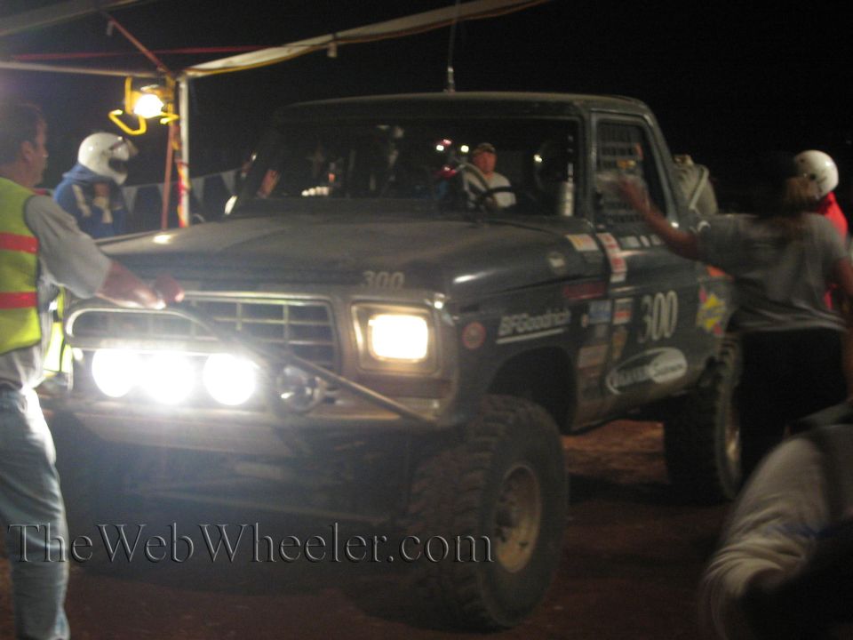 Front of black number 300 off-road truck with auxiliary lights lit