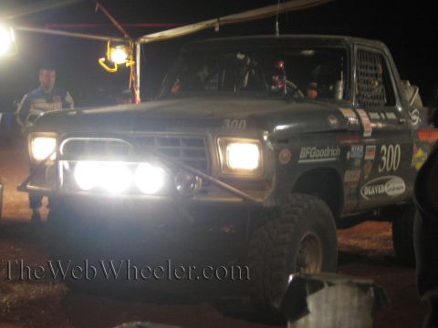 Front of number 300 off-road truck with bright lights at night