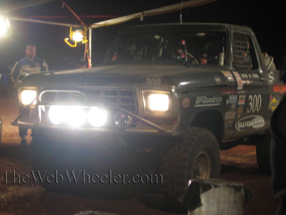 Front of number 300 off-road truck with bright lights at night