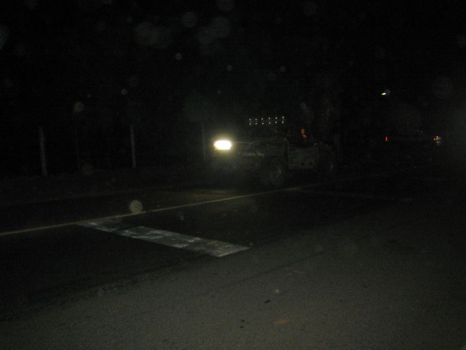 Distant off-road vehicle with single light on dark road at night