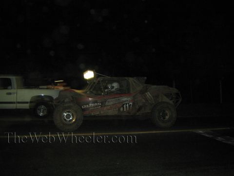 Muddy number 117 off-road race truck passing a pickup at night