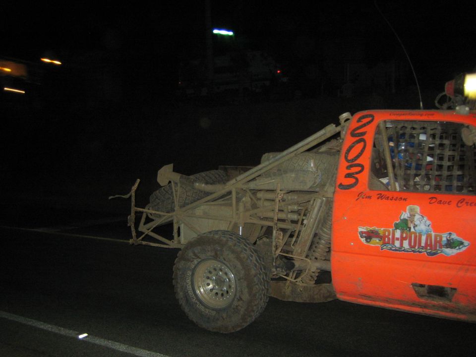 Orange muddy number 203 off-road race truck side view at night