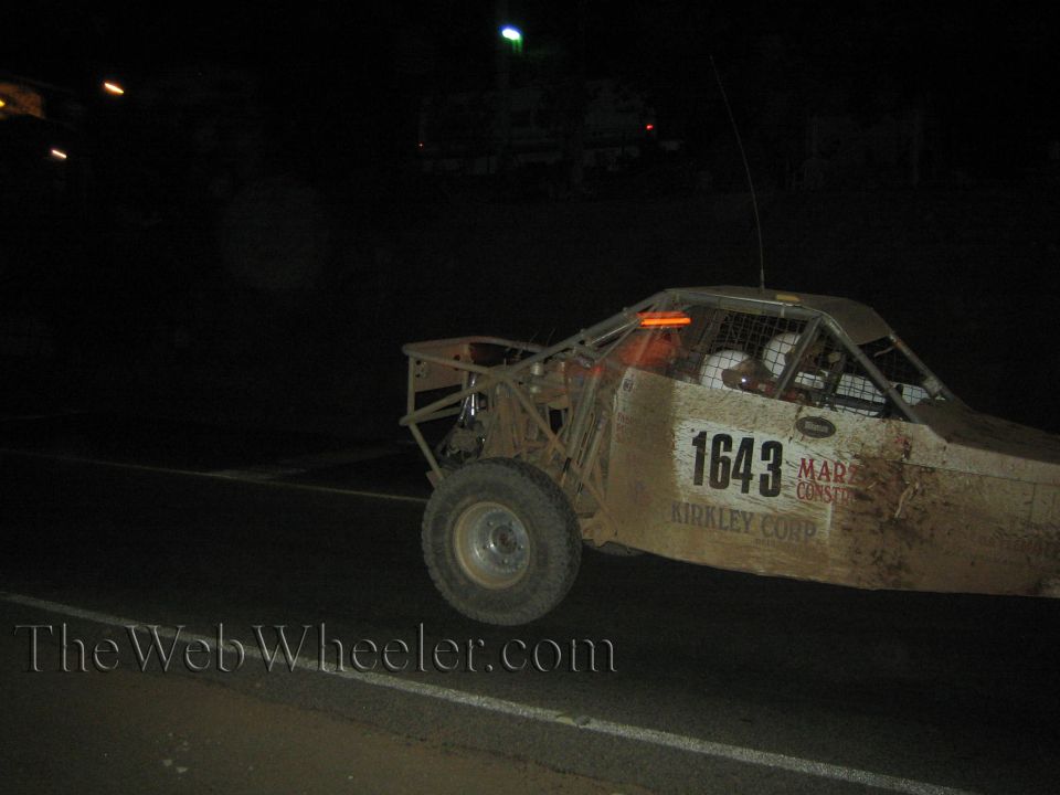 Muddy number 1643 off-road race truck side view on dark road at night