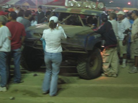 Dark blue off-road truck with roof light bar pushed through a crowd at night