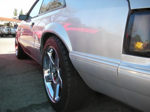 1998 Ford Crown Victoria - A silver coupe with chrome wheels is parked outdoors, with another vehicle visible in the background.