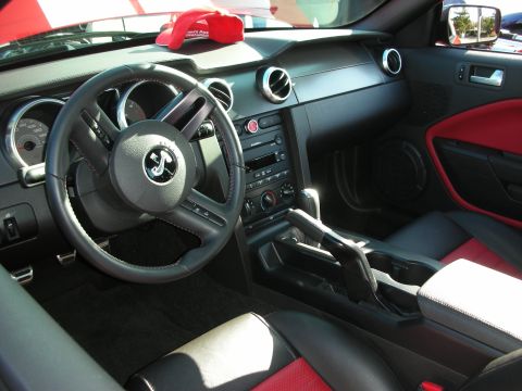 1998 Ford Crown Victoria - Modern Mustang interior featuring a pony-logo steering wheel, black-and-red seats and center console with shifter.