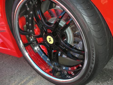 1998 Ford Crown Victoria - Detail of a red Ferrari's chrome-lipped black multi-spoke wheel over a drilled rotor with the prancing-horse cap.