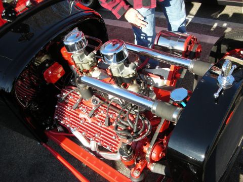 1998 Ford Crown Victoria - Detail of a polished hot rod V8 with twin chrome carburetors, finned valve covers and red block at a car meet.