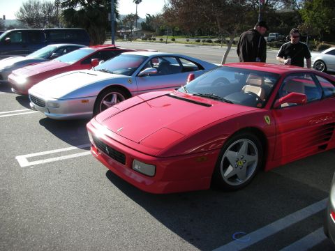 1998 Ford Crown Victoria - red Ferrari coupe parked front-angled beside a silver Ferrari and other cars at an outdoor car meet.