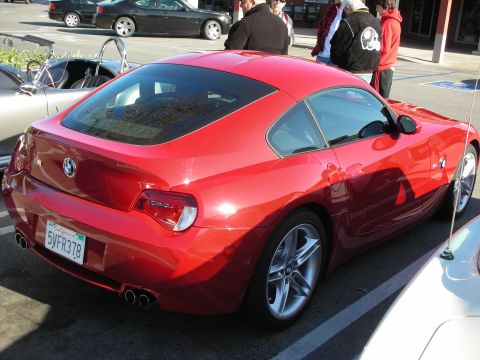 1998 Ford Crown Victoria - red BMW Z4 coupe seen from behind showing quad exhaust tips and California plate 5VFR378, with people nearby.