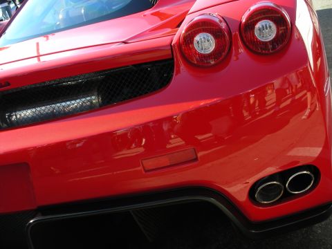 1998 Ford Crown Victoria - Detail of a red Ferrari Enzo's rear corner showing the twin round taillights, mesh vent and dual exhaust tips.