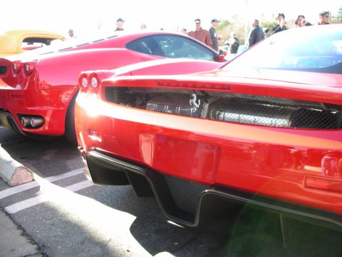 1998 Ford Crown Victoria - rear ends of two red Ferraris parked closely together, with a yellow car and crowd visible behind.