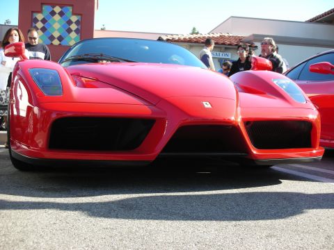 1998 Ford Crown Victoria - Low front three-quarter view of a red Ferrari Enzo with its sculpted nose and air intakes, spectators behind it.